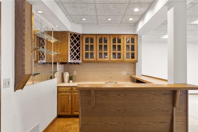 bar with light parquet floors, sink, a paneled ceiling, and decorative backsplash