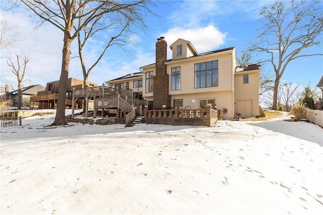 snow covered back of property featuring a deck