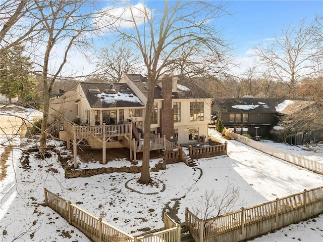 snow covered back of property featuring a deck