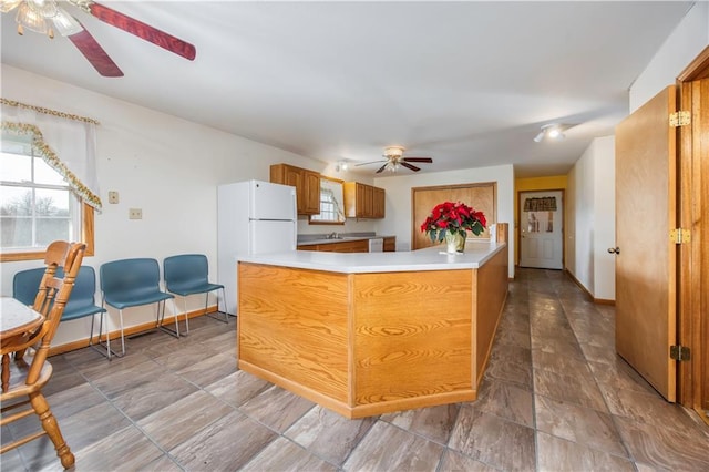 kitchen featuring ceiling fan, white fridge, and kitchen peninsula