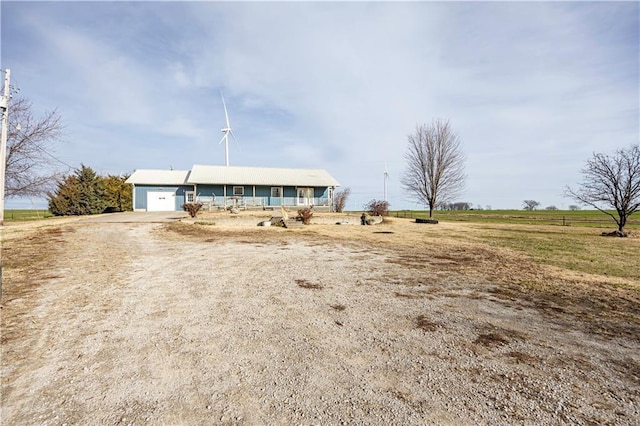 view of front facade featuring covered porch, a garage, and a rural view