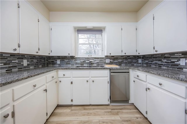 kitchen featuring light hardwood / wood-style floors, white cabinetry, dark stone counters, and sink