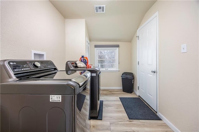 laundry room with light hardwood / wood-style floors and washing machine and clothes dryer