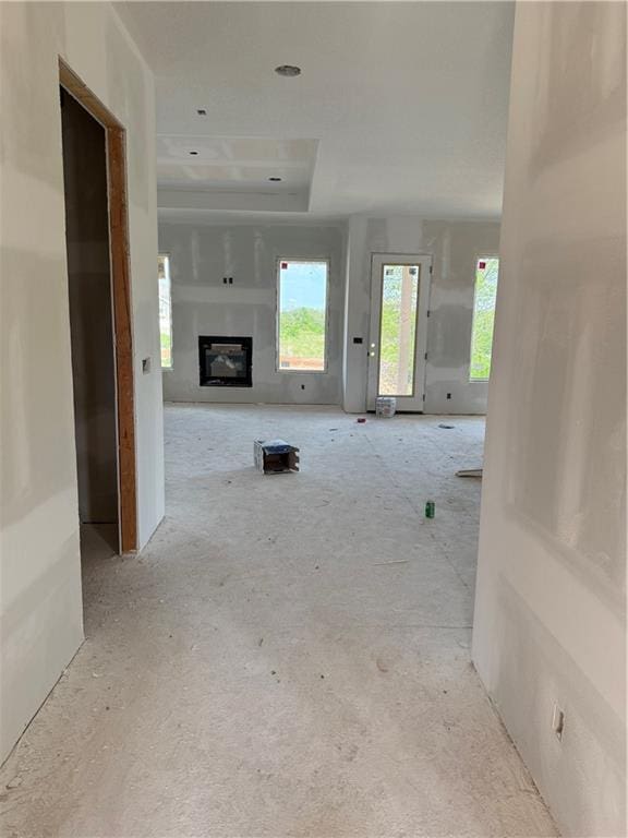 18405 Caenen St, Overland Park, KS 66013 - unfurnished living room featuring a glass covered fireplace and a tray ceiling