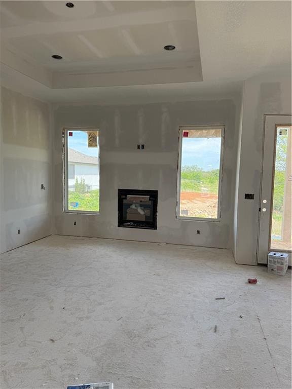 18405 Caenen St, Overland Park, KS 66013 - unfurnished living room featuring a glass covered fireplace and a raised ceiling