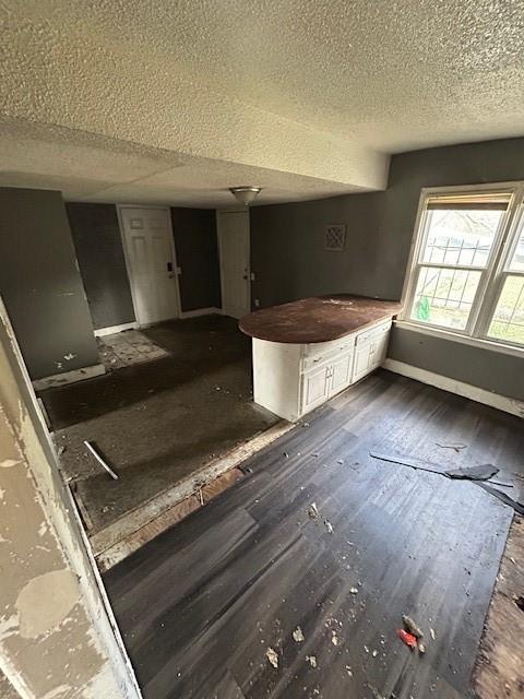 kitchen featuring dark hardwood / wood-style flooring, white cabinetry, and a textured ceiling