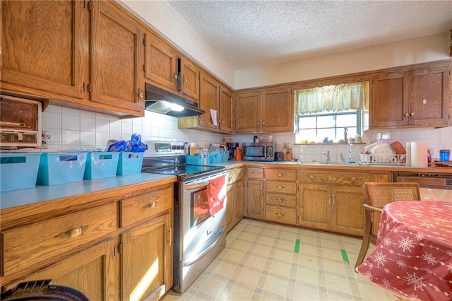 kitchen with a textured ceiling, appliances with stainless steel finishes, tasteful backsplash, and sink