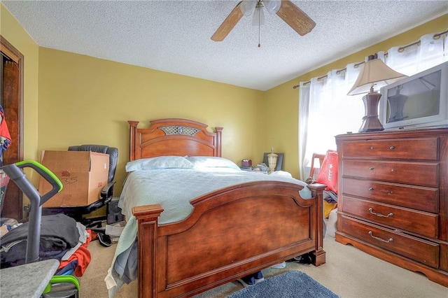 bedroom featuring ceiling fan, light colored carpet, and a textured ceiling