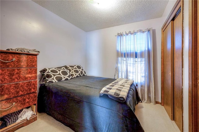 carpeted bedroom with a textured ceiling and a closet