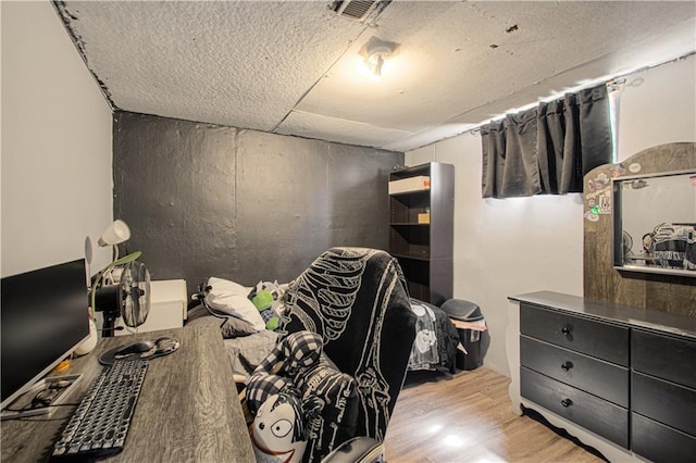 bedroom with visible vents, a textured ceiling, and wood finished floors