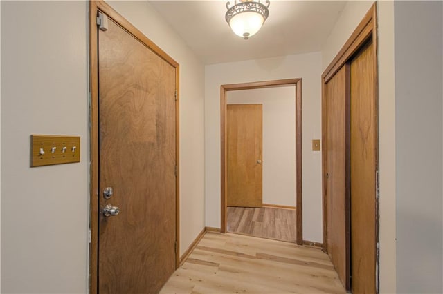 hallway featuring baseboards and light wood finished floors