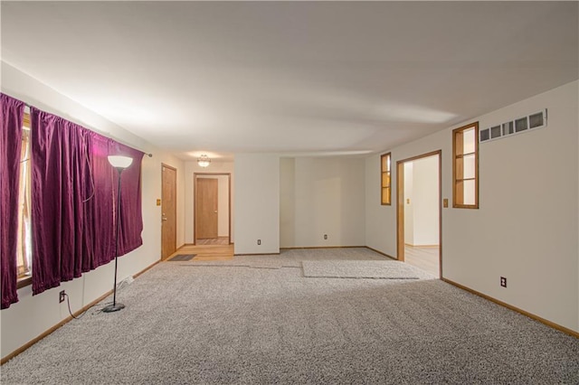 unfurnished room featuring baseboards, light colored carpet, and visible vents