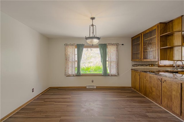 unfurnished dining area with visible vents, a sink, dark wood-style flooring, and baseboards