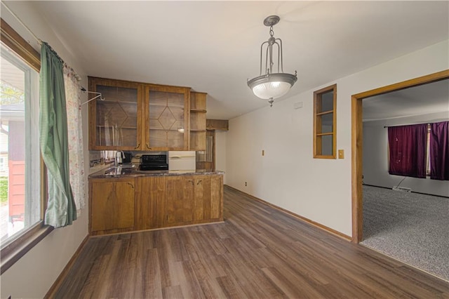 kitchen featuring brown cabinetry, dark wood-style flooring, a peninsula, and glass insert cabinets