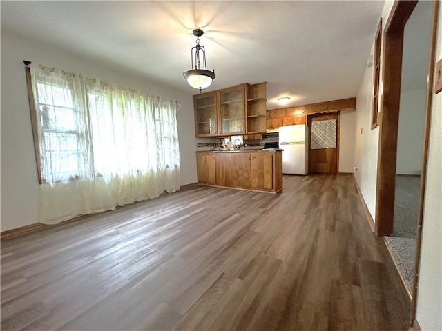 kitchen with brown cabinetry, freestanding refrigerator, open shelves, a peninsula, and light wood-style flooring