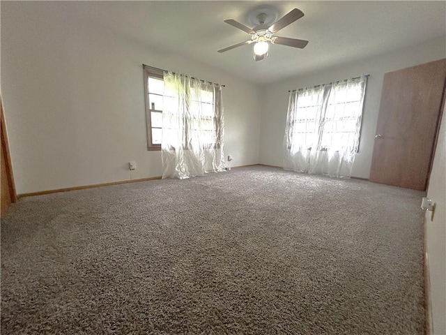 carpeted spare room featuring a ceiling fan, baseboards, and plenty of natural light