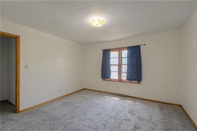carpeted spare room featuring baseboards