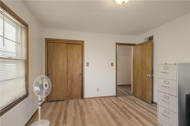 unfurnished bedroom with a closet, baseboards, visible vents, and light wood-type flooring