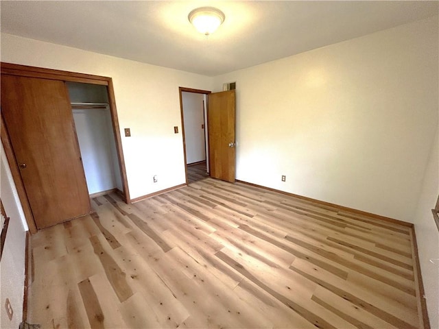 unfurnished bedroom with a closet, light wood-style flooring, baseboards, and visible vents