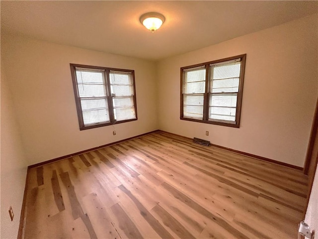 empty room featuring baseboards and light wood-style floors