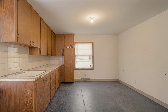 kitchen with a sink, light countertops, tasteful backsplash, and brown cabinetry
