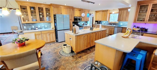 kitchen with an island with sink, hanging light fixtures, stainless steel appliances, a breakfast bar area, and decorative backsplash