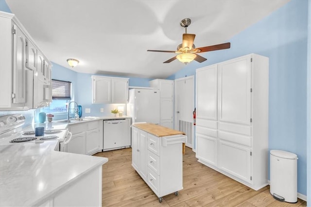 kitchen with sink, white appliances, white cabinets, and a kitchen island