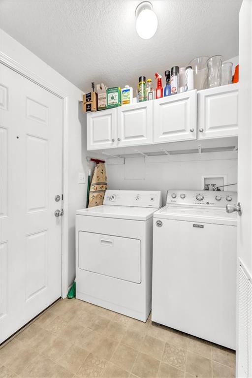 washroom with independent washer and dryer, cabinets, and a textured ceiling