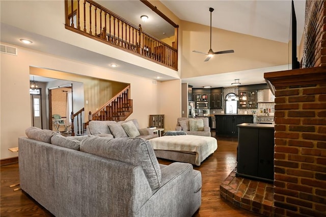 living room featuring high vaulted ceiling, a fireplace, ceiling fan, and dark wood-type flooring