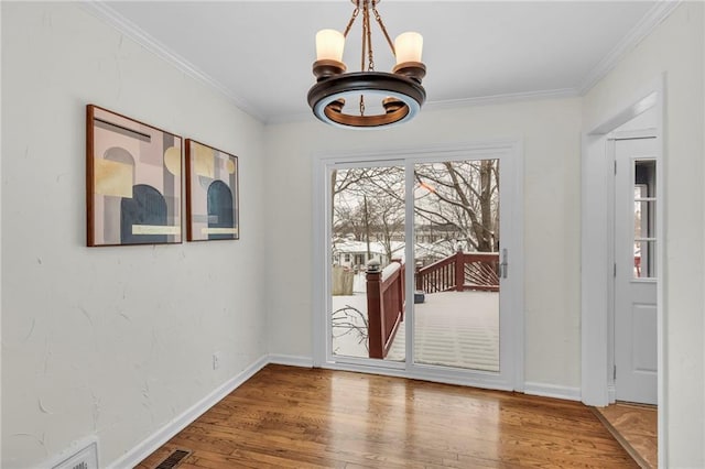 doorway with crown molding, wood-type flooring, and a chandelier