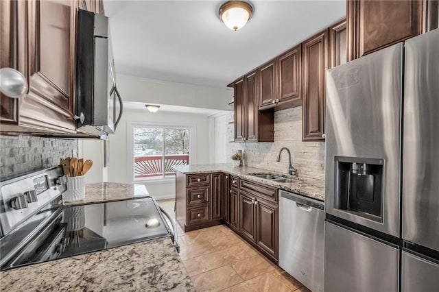 kitchen featuring light stone countertops, backsplash, stainless steel appliances, and sink