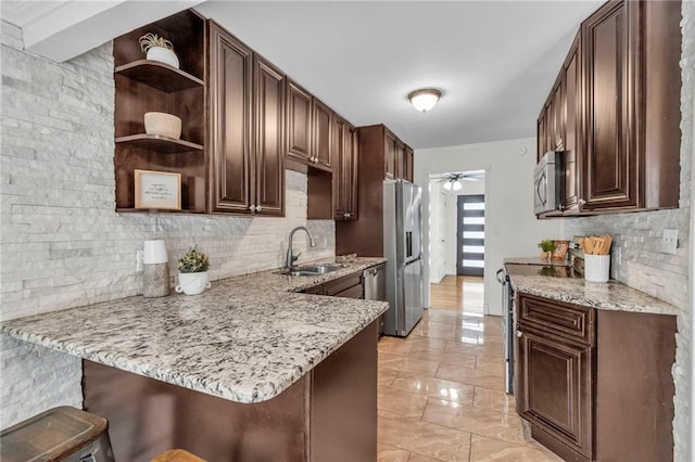 kitchen with sink, a breakfast bar area, light stone countertops, and kitchen peninsula