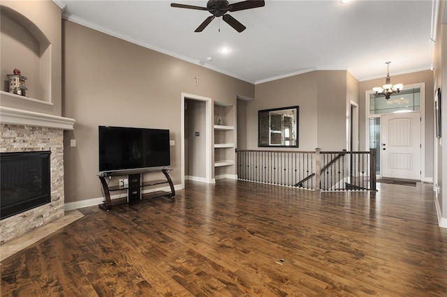 unfurnished living room with built in features, ornamental molding, a stone fireplace, and dark wood-type flooring