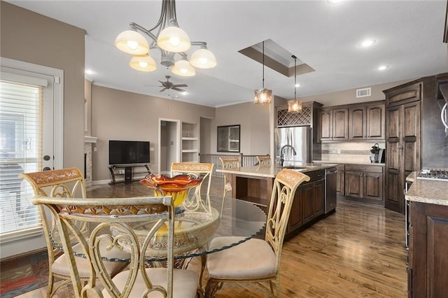 dining space with a wealth of natural light, dark hardwood / wood-style flooring, and ceiling fan with notable chandelier