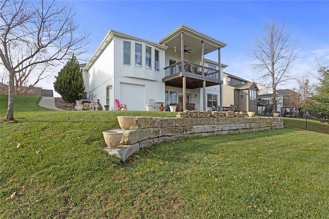 rear view of property featuring a yard, ceiling fan, a balcony, and a garage