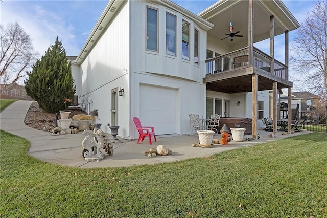 rear view of house featuring a lawn, ceiling fan, a hot tub, a garage, and a patio