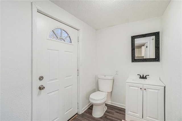 bathroom with hardwood / wood-style floors, vanity, a textured ceiling, and toilet