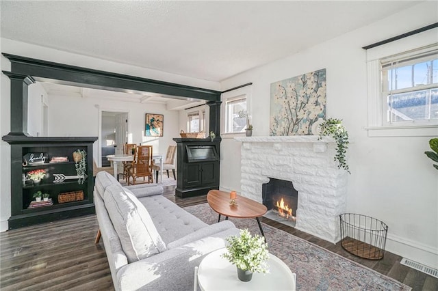 living room featuring dark hardwood / wood-style flooring and a stone fireplace