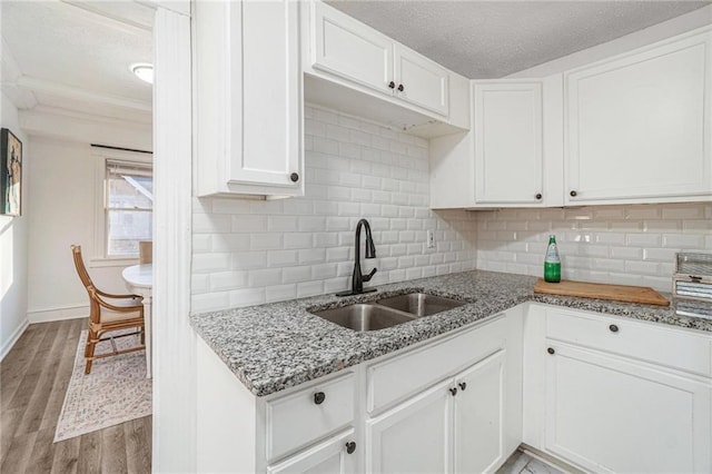 kitchen featuring a textured ceiling, light wood-type flooring, white cabinetry, and sink