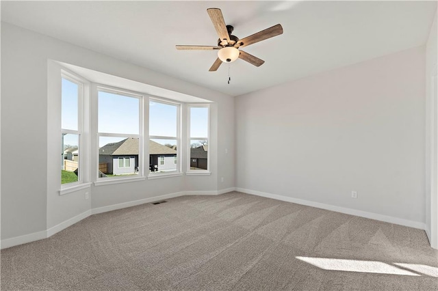 unfurnished room with carpet floors, visible vents, ceiling fan, and baseboards