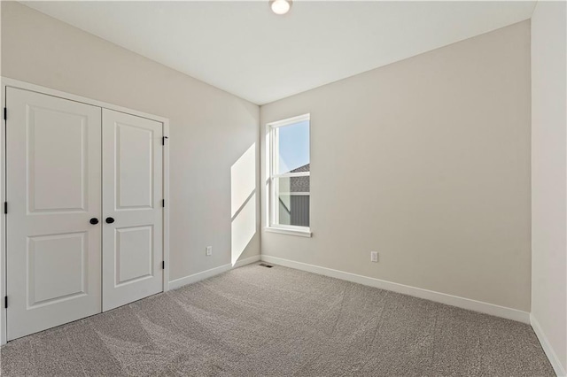 unfurnished bedroom with light colored carpet and a closet