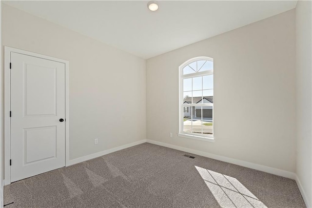 spare room featuring carpet floors, visible vents, and baseboards