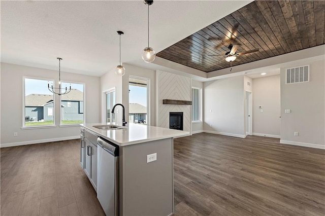 kitchen with sink, pendant lighting, stainless steel dishwasher, and a center island with sink