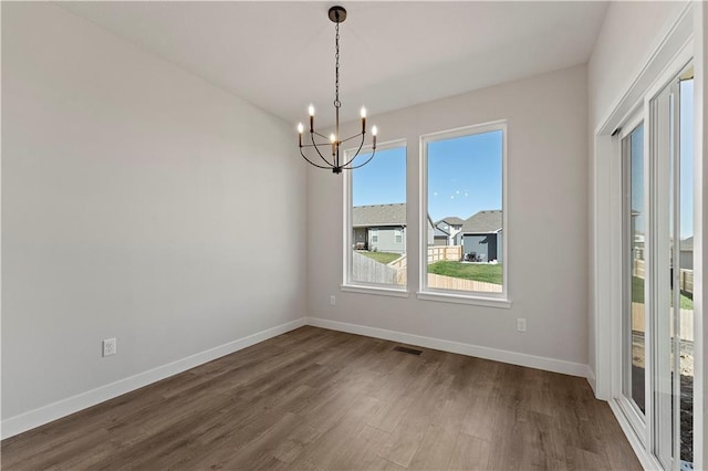 empty room featuring visible vents, dark wood finished floors, baseboards, and an inviting chandelier