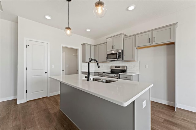 kitchen featuring decorative light fixtures, dark hardwood / wood-style floors, sink, an island with sink, and stainless steel appliances