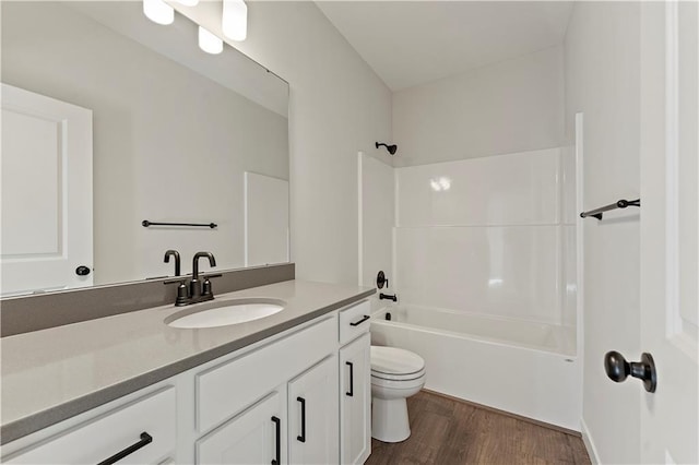 bathroom featuring toilet, vanity, wood finished floors, and washtub / shower combination