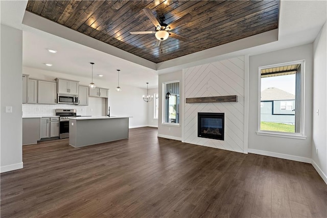 unfurnished living room featuring a fireplace, a wealth of natural light, a tray ceiling, and wooden ceiling