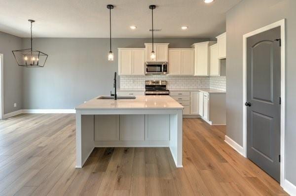 kitchen featuring a sink, backsplash, appliances with stainless steel finishes, and white cabinets