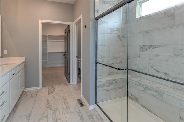 bathroom featuring baseboards, toilet, a stall shower, marble finish floor, and vanity