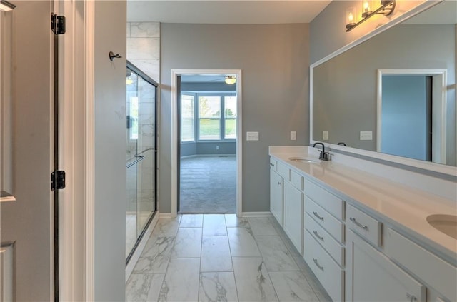 bathroom with baseboards, double vanity, a sink, a shower stall, and marble finish floor